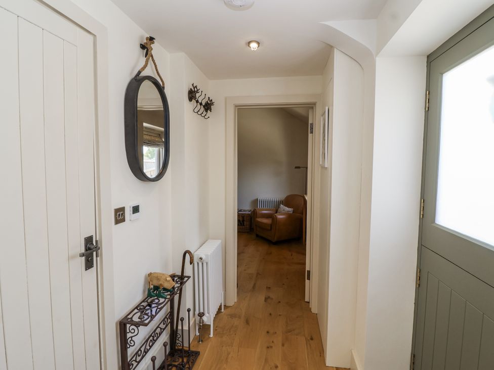 A hallway with a mirror and a coat rack at The Little Loft in Burford