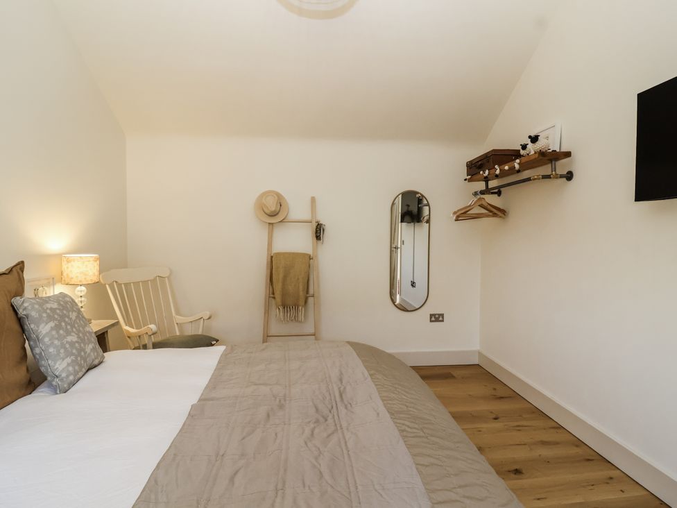 A bedroom with a bed and chair at The Little Loft in Burford