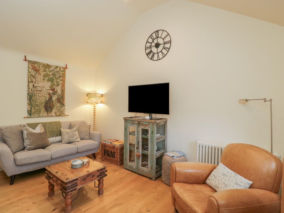 A living room with a sofa and television at The Little Loft in Burford