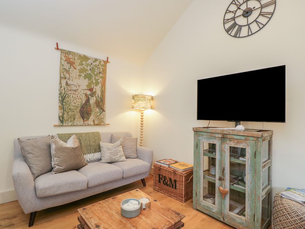 A living room with a sofa and television at The Little Loft in Burford