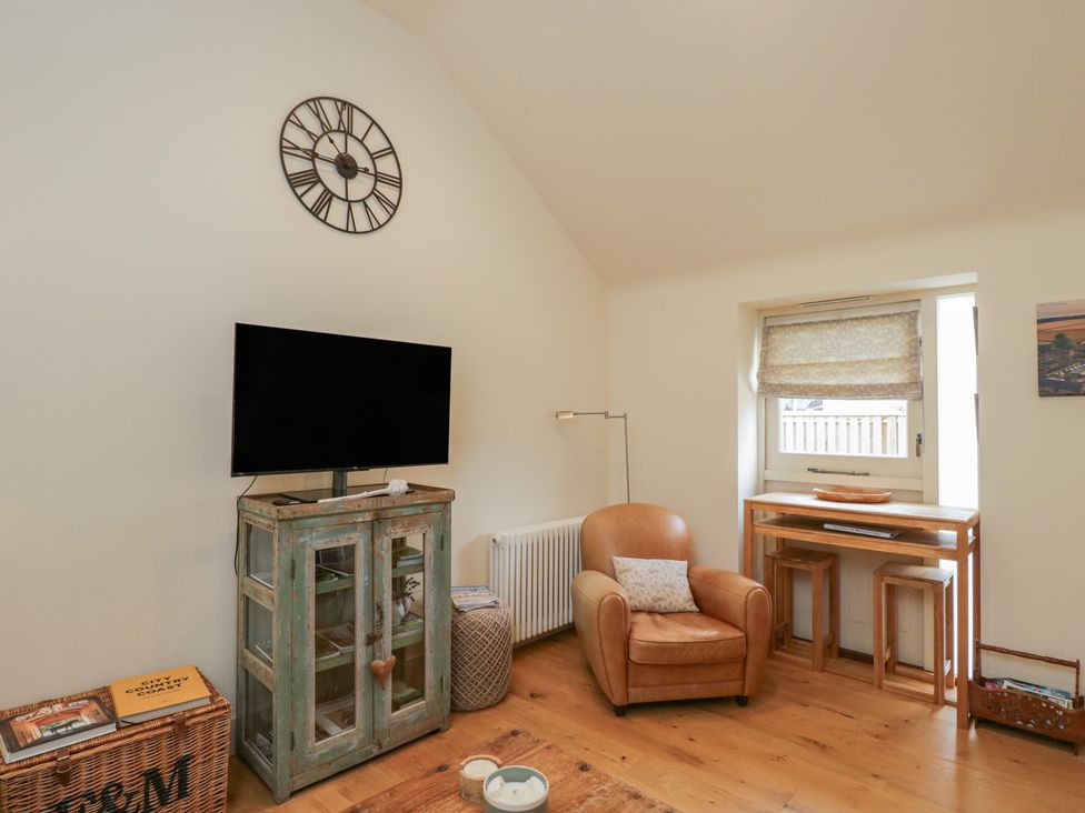 A living room with a television and a chair at The Little Loft in Burford