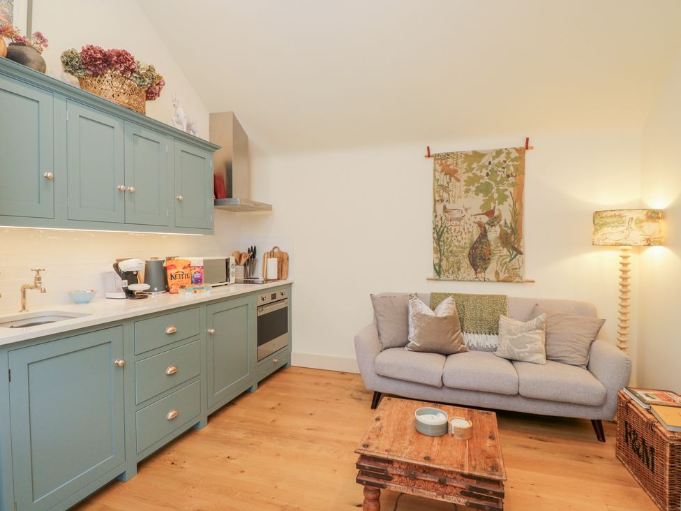 A kitchen with blue cabinets and a sofa at The Little Loft in Burford