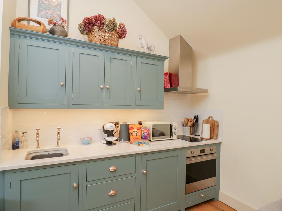 A kitchen with cabinets and appliances at The Little Loft in Burford