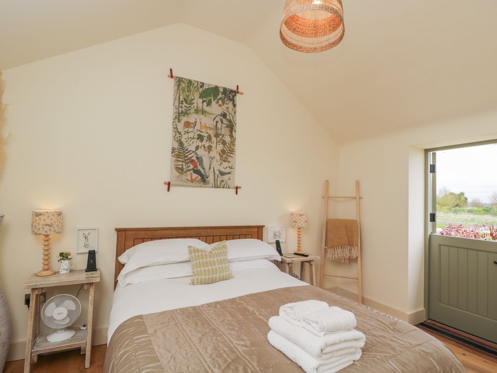 A bedroom with a bed and artwork on the wall at The Little Loft in Burford