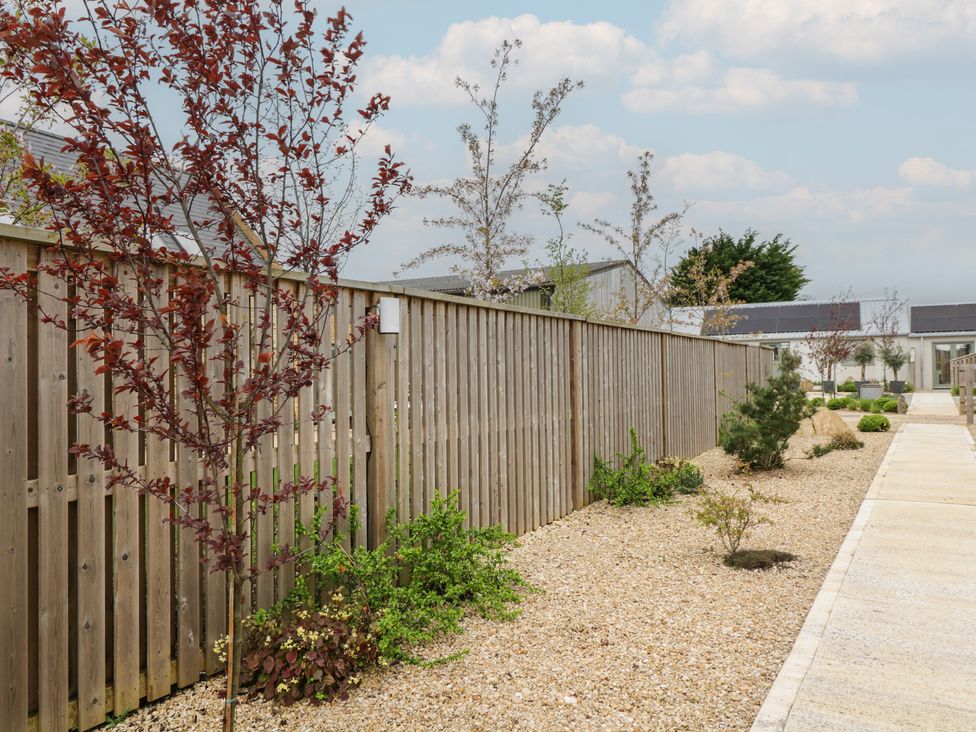 A garden with a wooden fence and gravel path at The Little Loft in Burford
