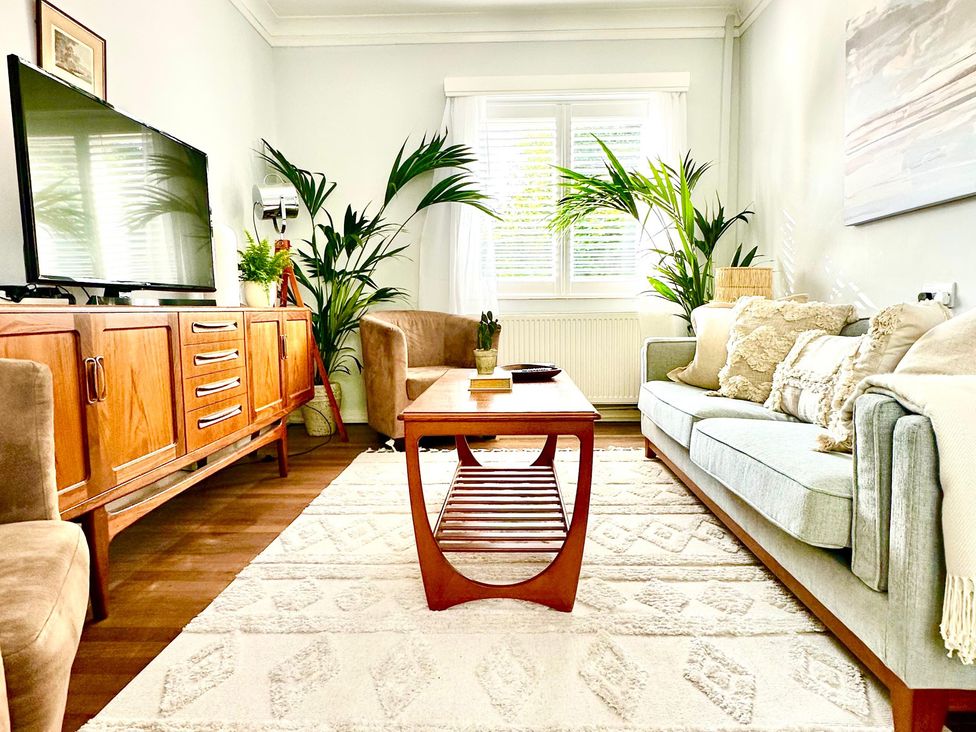 A living room with a sofa, table, and TV at The Shingles in Sandown