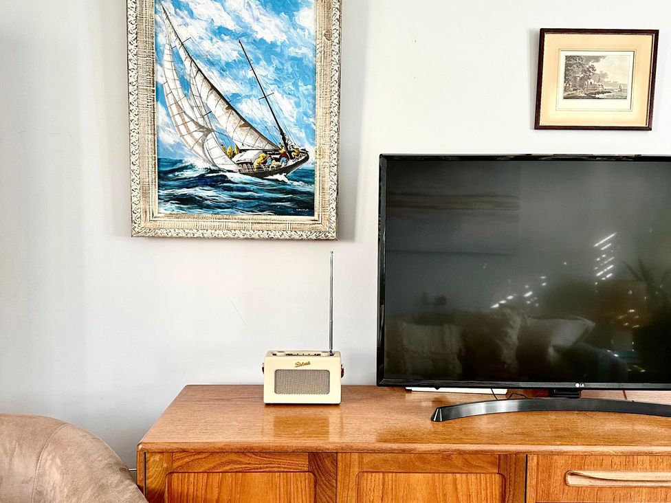 A living room with a television and radio on a cabinet at The Shingles in Sandown