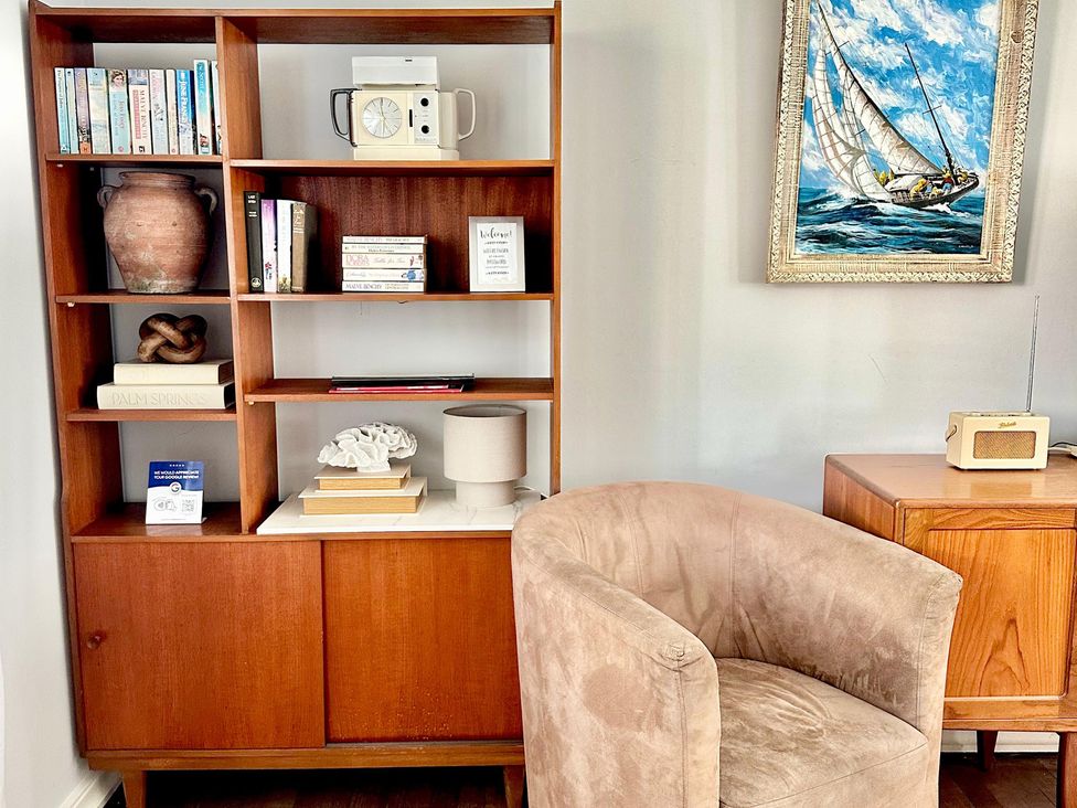 A living room with a bookshelf and a chair at The Shingles in Sandown