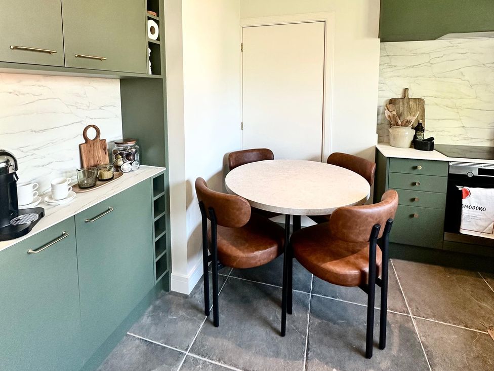 A kitchen with cabinets and a circular table at The Shingles in Sandown