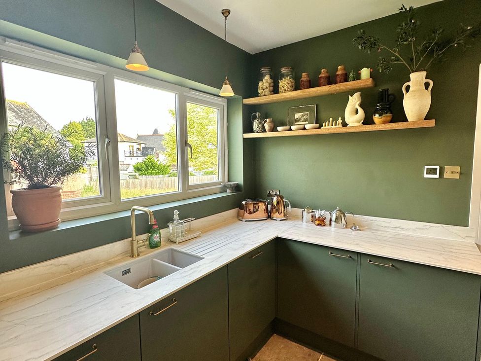 A kitchen featuring a sink and shelves with jars and vases at The Shingles in Sandown