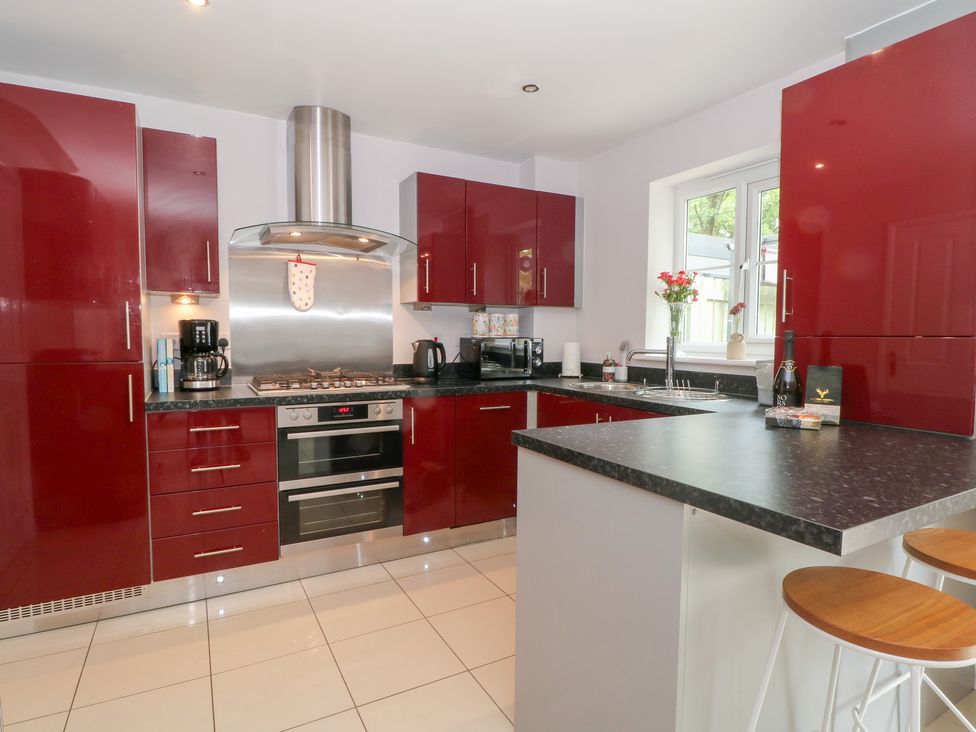 A kitchen with red cabinets and black countertop at Woodland View in Buxton