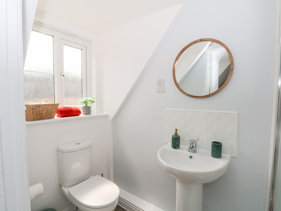 A bathroom with a toilet, sink, and mirror at Woodland View in Buxton