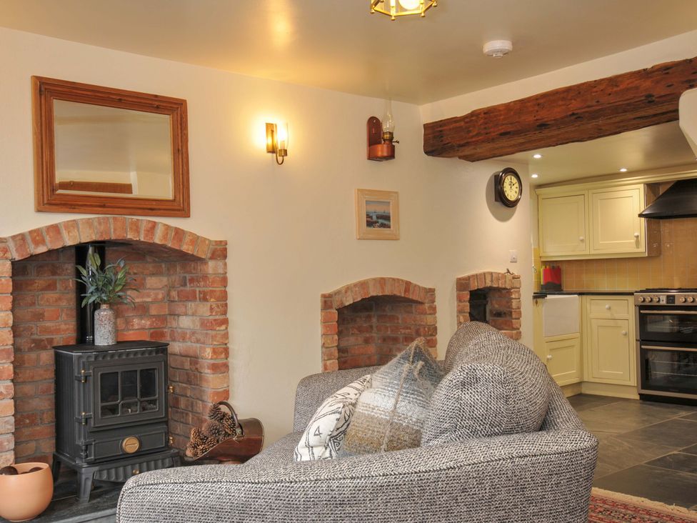 A living room with a fireplace and kitchen area at Jolly Crabber in Porthpean near St Austell