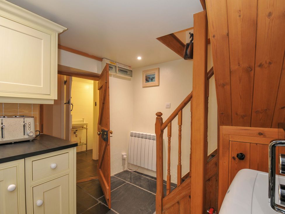 A hallway with a staircase and kitchen features at Jolly Crabber in Porthpean near St Austell