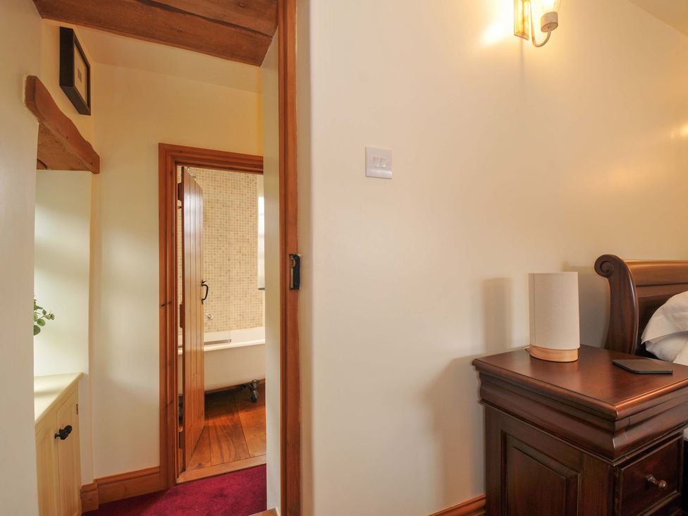 A bedroom with a nightstand and door to bathroom at Jolly Crabber in Porthpean near St Austell