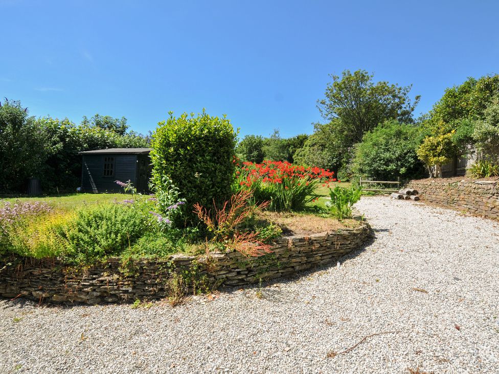 A garden with a shed and flower bed at Jolly Crabber in Porthpean near St Austell