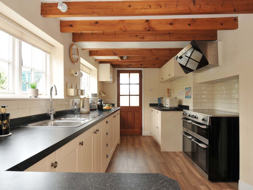 A kitchen with cabinets, sink, and oven at Smugglers in Porthpean near St Austell