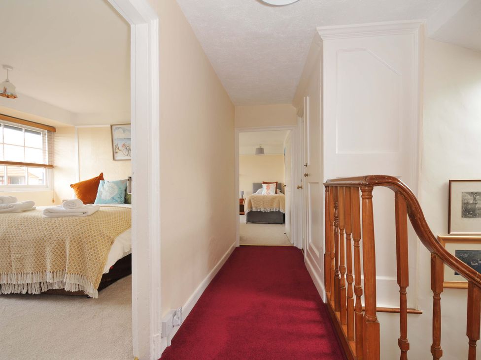 A hallway with stairs and rooms on either side at Smugglers in Porthpean near St Austell