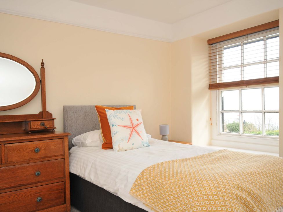 A bedroom with a bed and a wooden dresser at Smugglers in Porthpean near St Austell