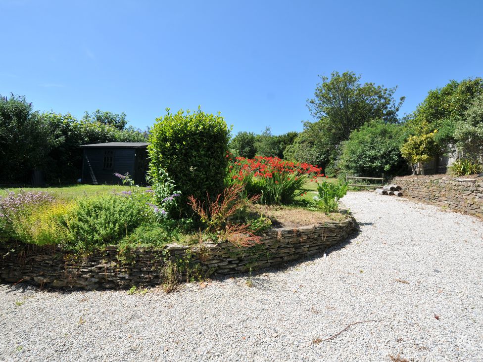 A garden with a gravel pathway and flower beds at Smugglers, Porthpean near St Austell