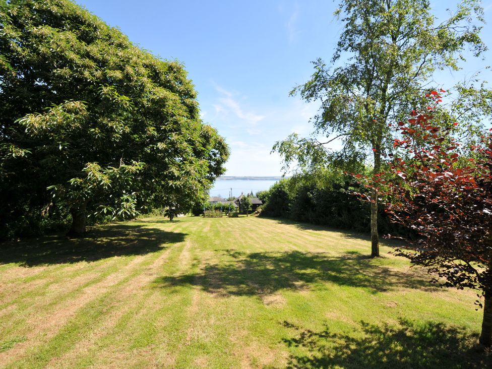 A garden with trees and water view at Smugglers in Porthpean near St Austell