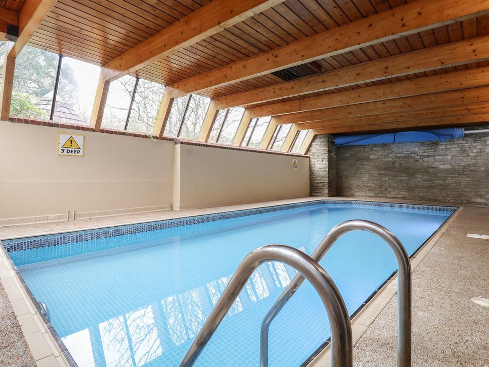 An indoor pool area with wooden beams and a warning sign at Watermouth Castle, Bassett Apartment Berrynarbor near Ilfracombe