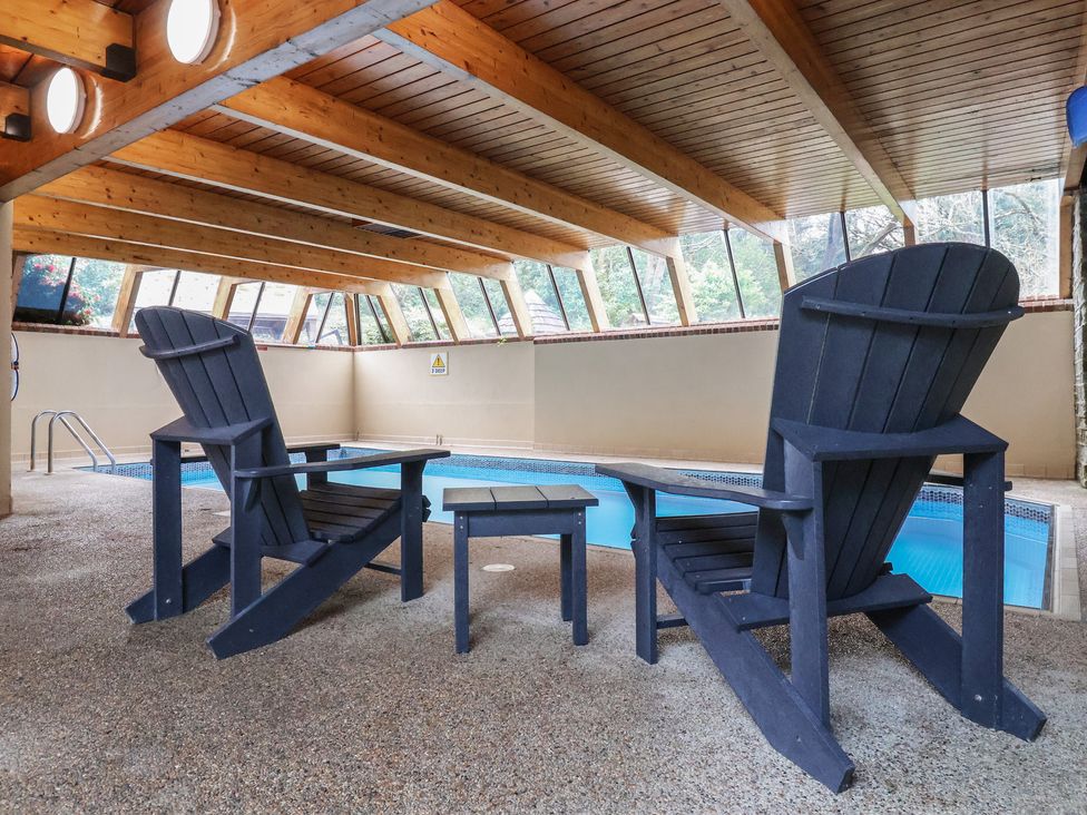An indoor pool area with chairs and a side table at Watermouth Castle, Clock Tower Apartment in Berrynarbor near Ilfracombe