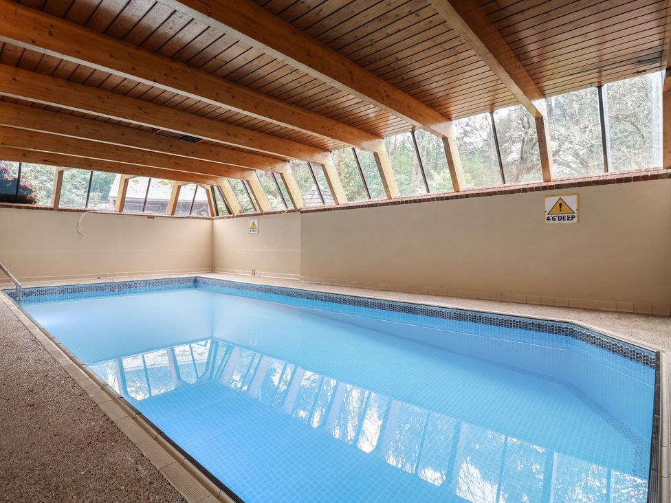 An indoor swimming pool with wooden beams and windows at Watermouth Castle, Clock Tower Apartment, Berrynarbor near Ilfracombe