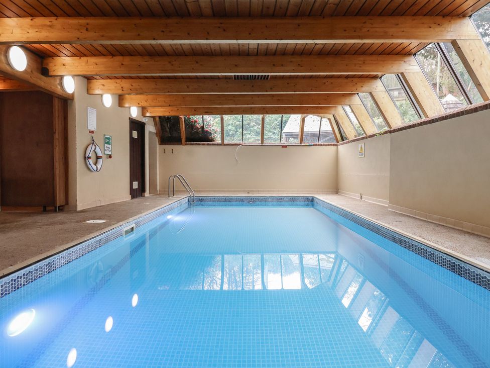An indoor pool with a wooden ceiling and large windows at Watermouth Castle, Clock Tower Apartment Berrynarbor near Ilfracombe