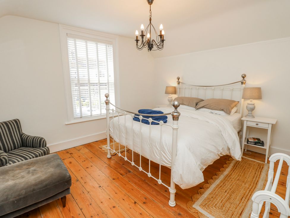 A bedroom with a bed, side table and chair at 4 Copse Lane in Freshwater