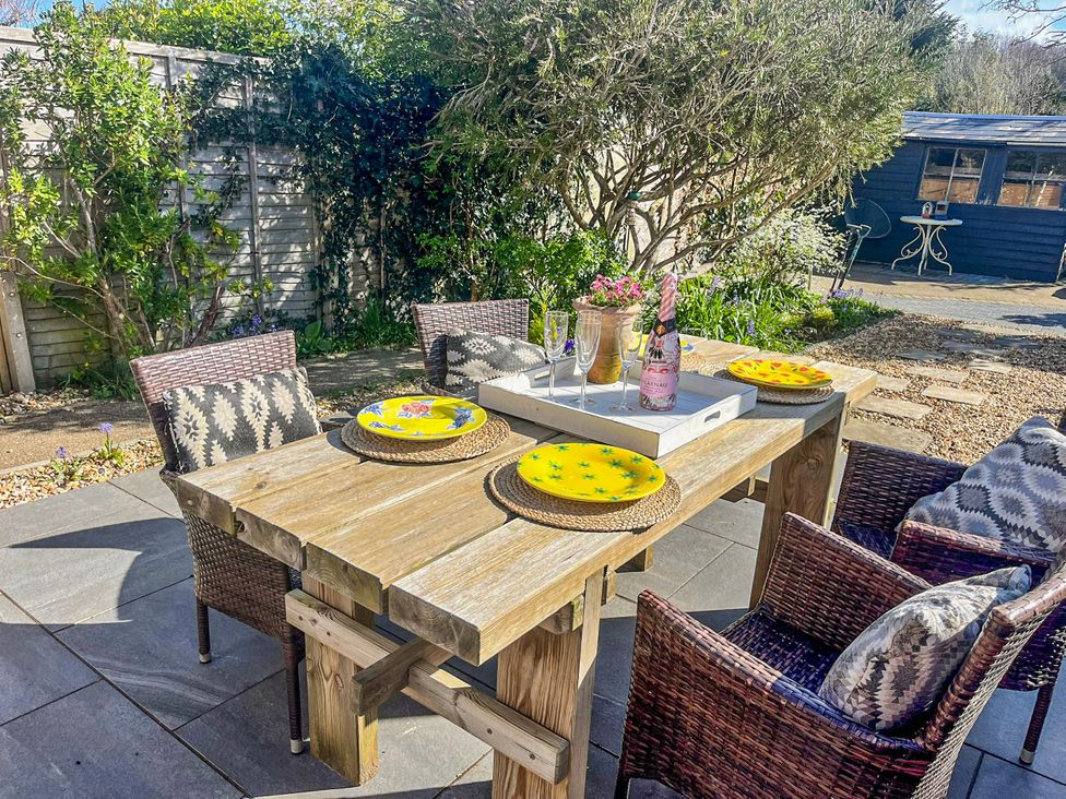 A dining table with chairs and plates in the garden at 4 Copse Lane Freshwater