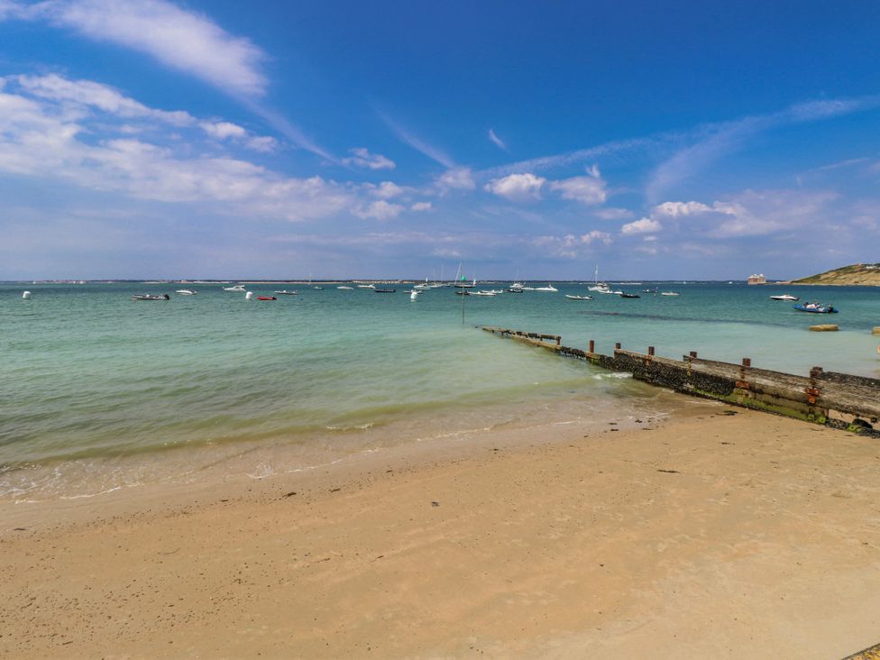 A beach with boats and a pier at 4 Copse Lane Freshwater