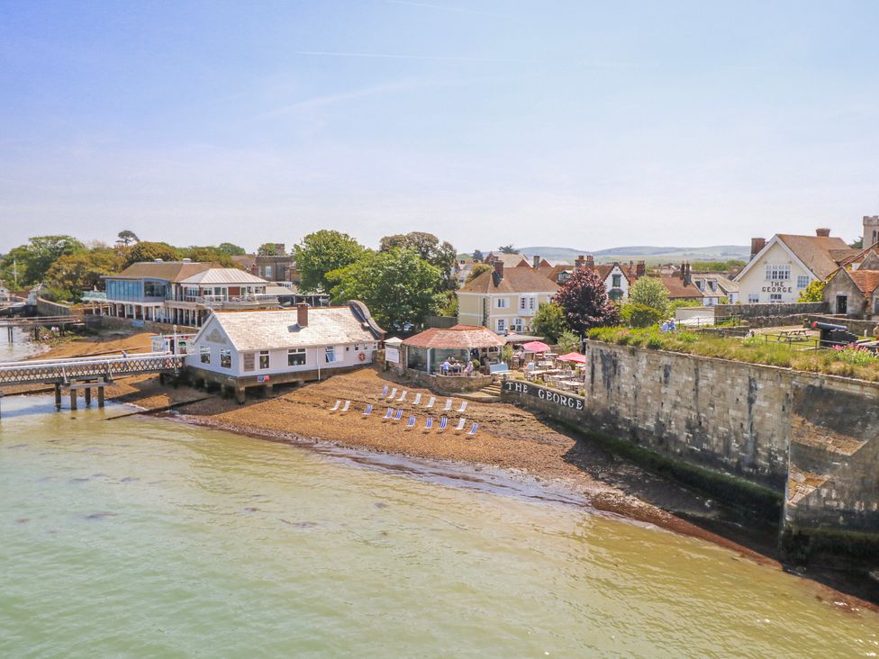 A beach with chairs and buildings by the water at 4 Copse Lane in Freshwater