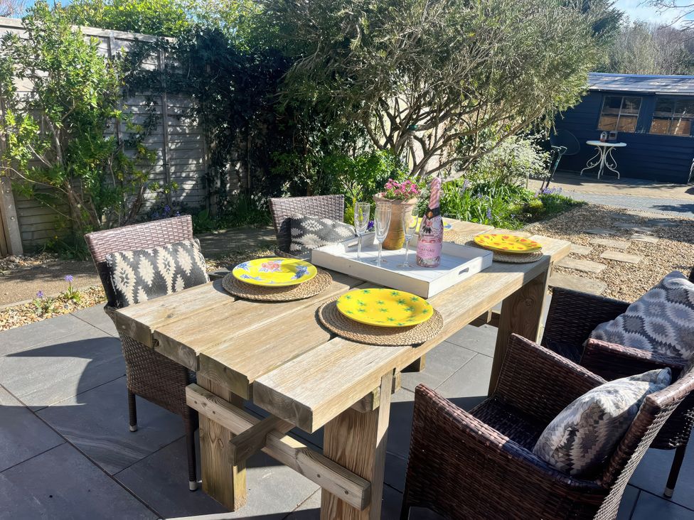 A garden dining setup with a wooden table and chairs at 4 Copse Lane Freshwater
