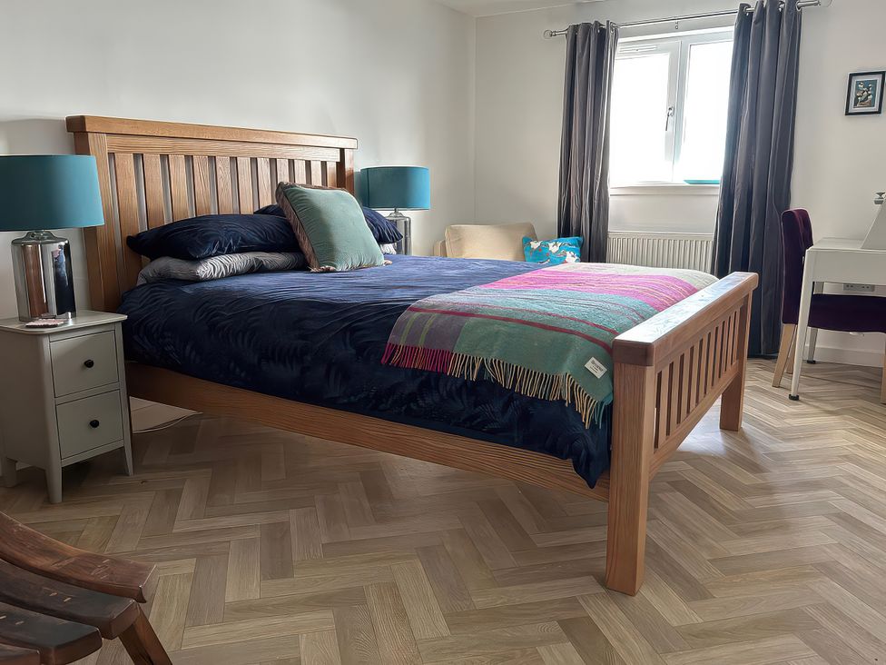 A bedroom with a wooden bed and a desk at Duart At The Sea Auckengill John O Groats