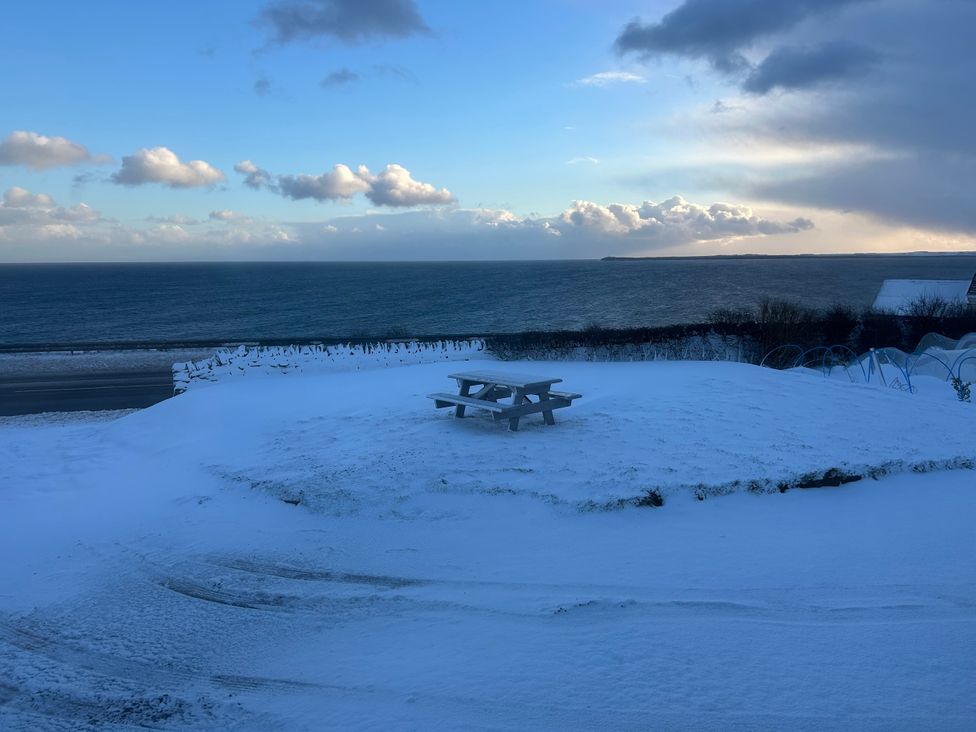 A snowy area with a bench and a view of the sea at Duart At The Sea Auckengill John O Groats