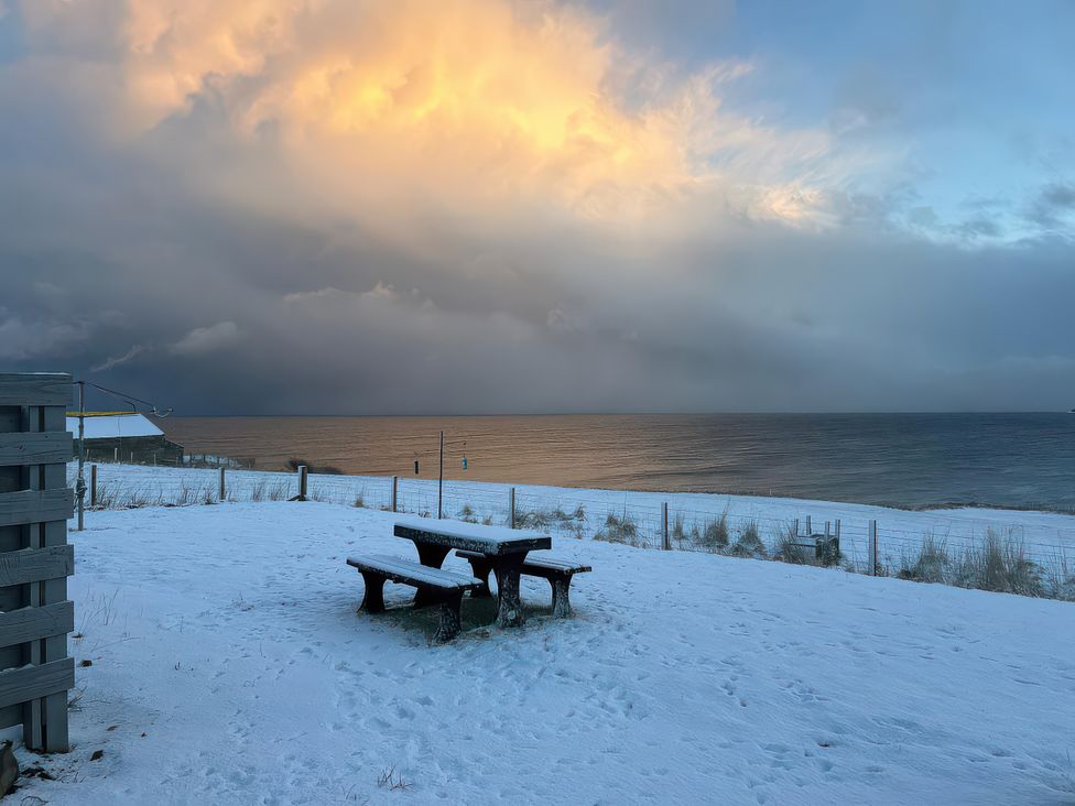 A picnic table and benches on snow by the ocean at Duart At The Sea Auckengill John O Groats