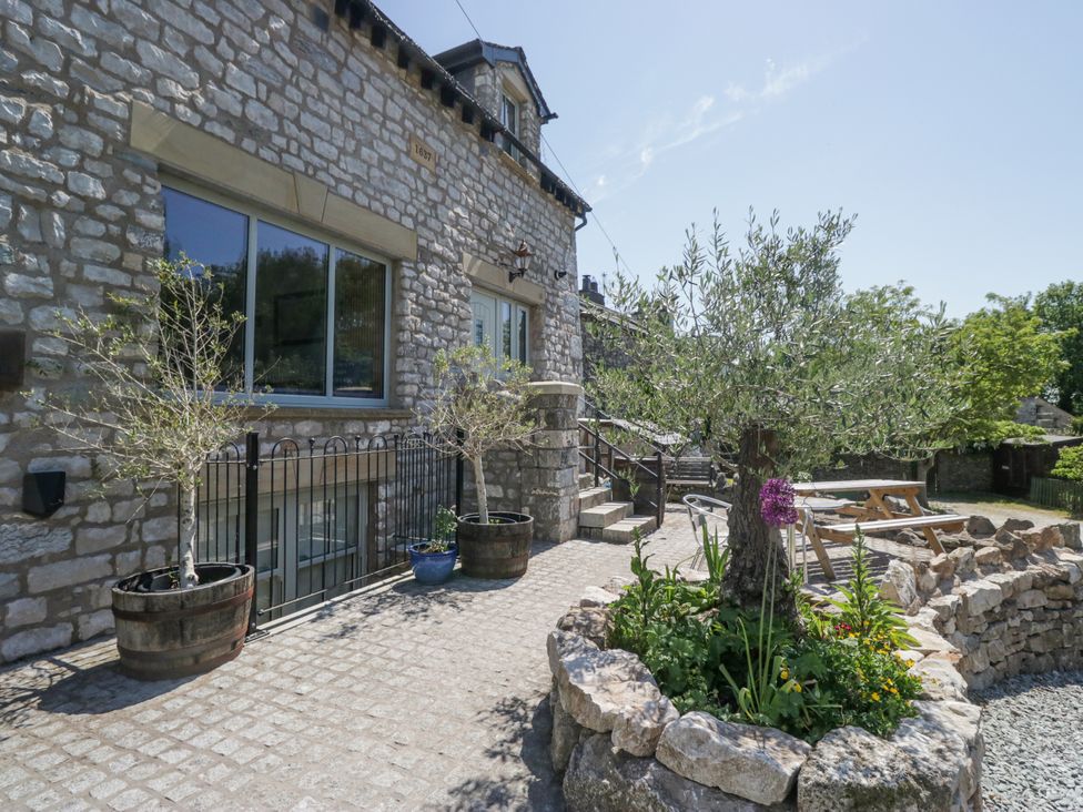 A stone building with a garden and planters at The Old Watermill in Cartmel