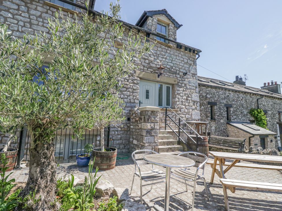 An outdoor area with a stone wall and furniture at The Old Watermill in Cartmel