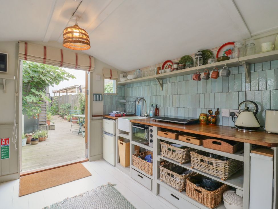 A kitchen with a sink and shelves at The Artist's Cabin By The Sea in Herne Bay
