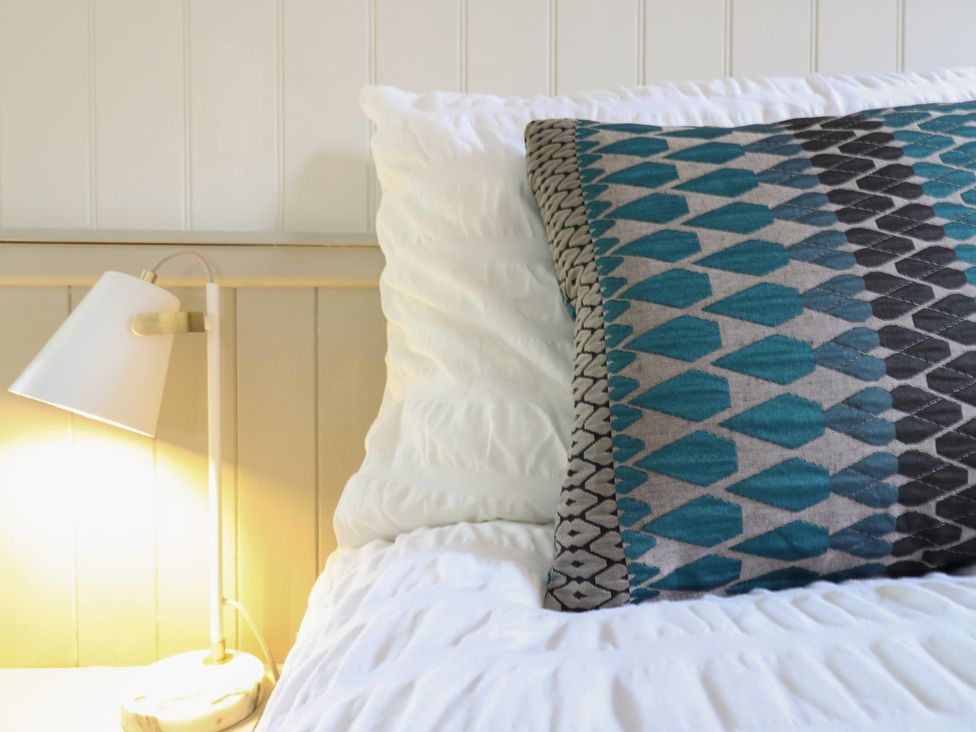 A bed with a patterned pillow and lamp at The Artist's Cabin By The Sea Herne Bay
