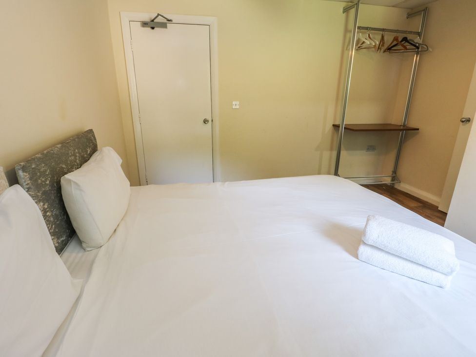 A bedroom with a bed, towels, and a clothes rack at The Bevan in Bontnewydd, Gwynedd
