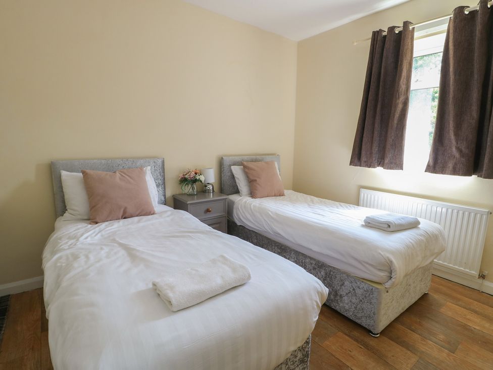A bedroom with two beds and a nightstand at The Bevan in Bontnewydd, Gwynedd