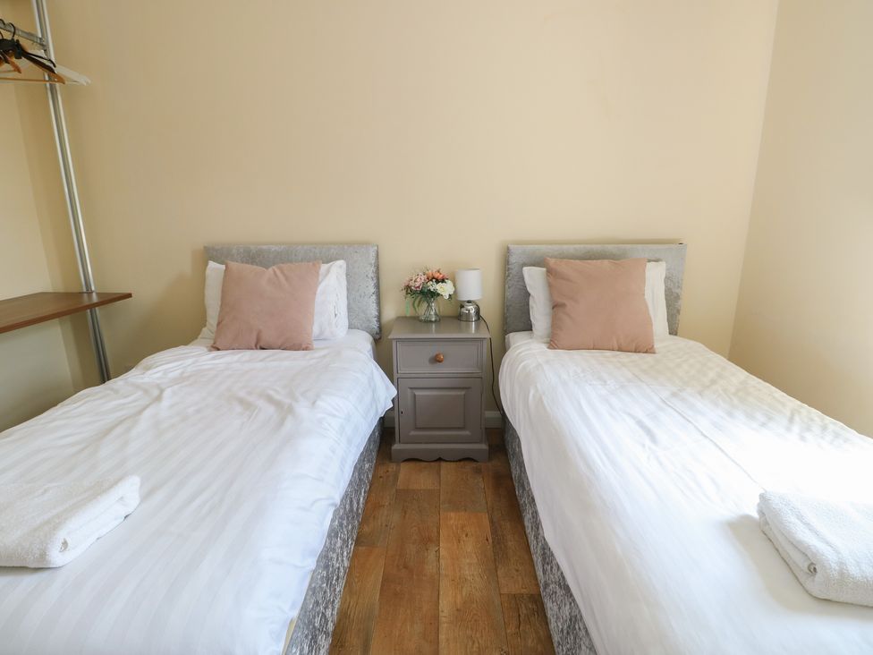 A bedroom with two single beds and a bedside table at The Bevan in Bontnewydd, Gwynedd