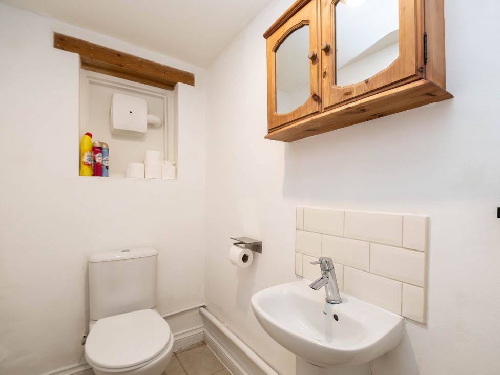 A bathroom with a toilet, sink and mirror cabinet at Gildridge Whitesmith near East Hoathly
