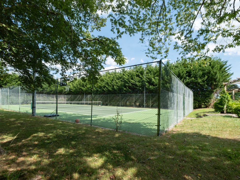 A tennis court surrounded by trees at Gildridge in Whitesmith near East Hoathly