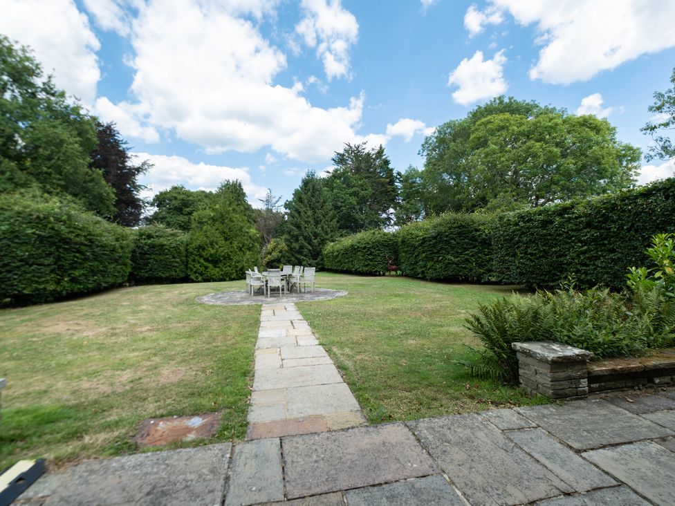 A garden with a table and chairs surrounded by hedges at Gildridge Whitesmith near East Hoathly
