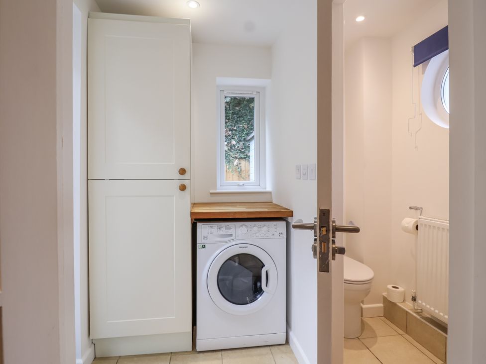 A laundry room with a washing machine and a toilet at Mariners Rest in Gorran Haven