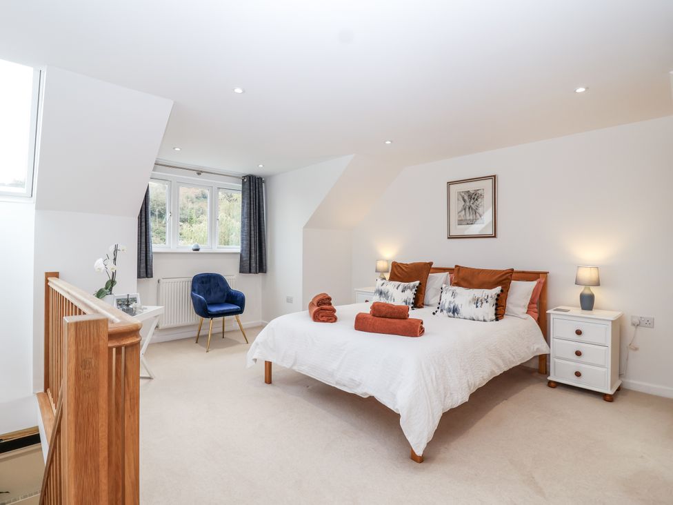 A bedroom with a bed, nightstands, and a chair at Mariners Rest in Gorran Haven