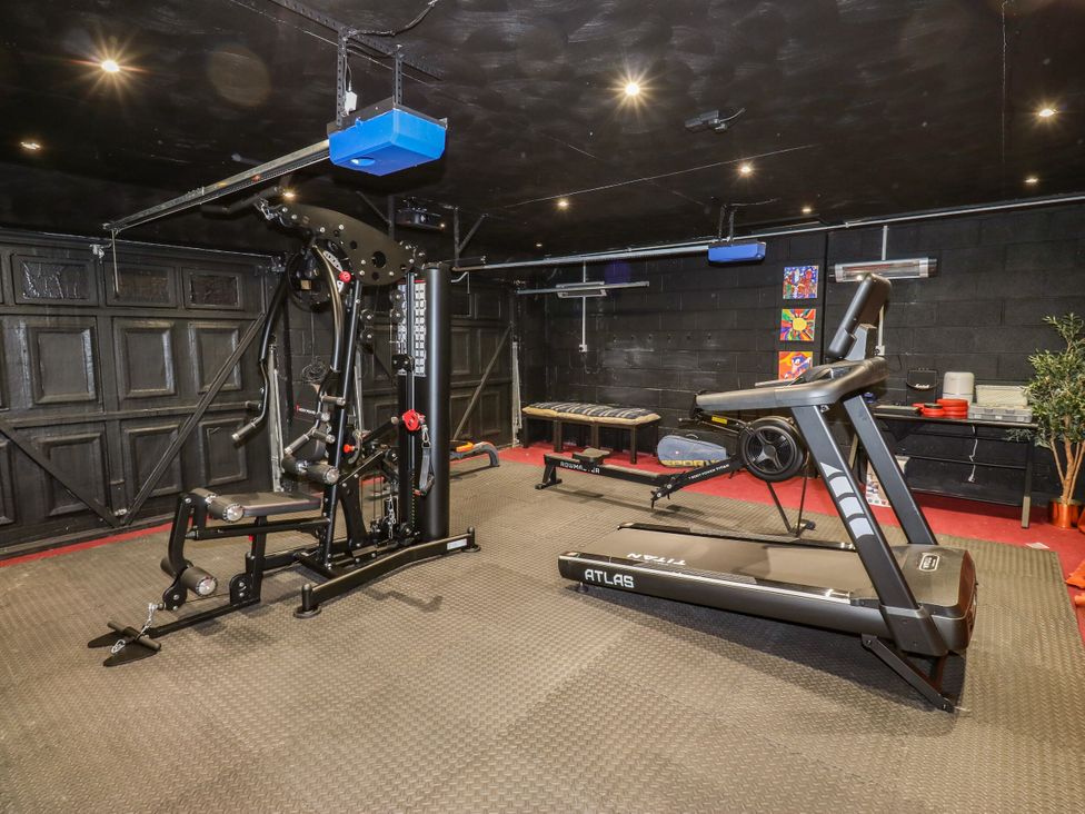 A gym with weight training machine, treadmill, and exercise bench at Akila in Grasscroft near Greenfield